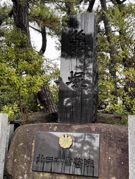 A stone fudezuka memorial among trees, inscribed with 筆塚.