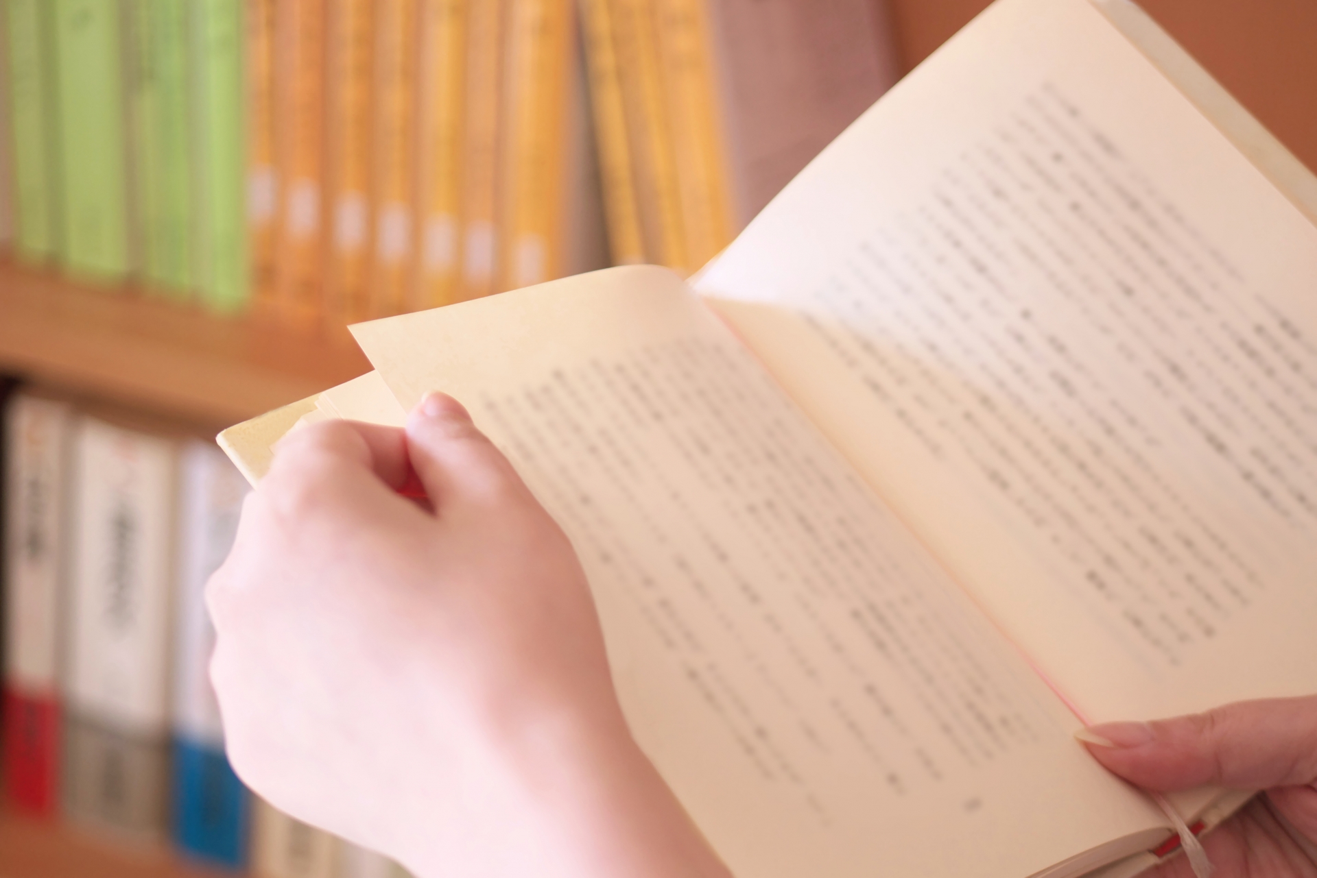 Hands holding an open Japanese-language book.