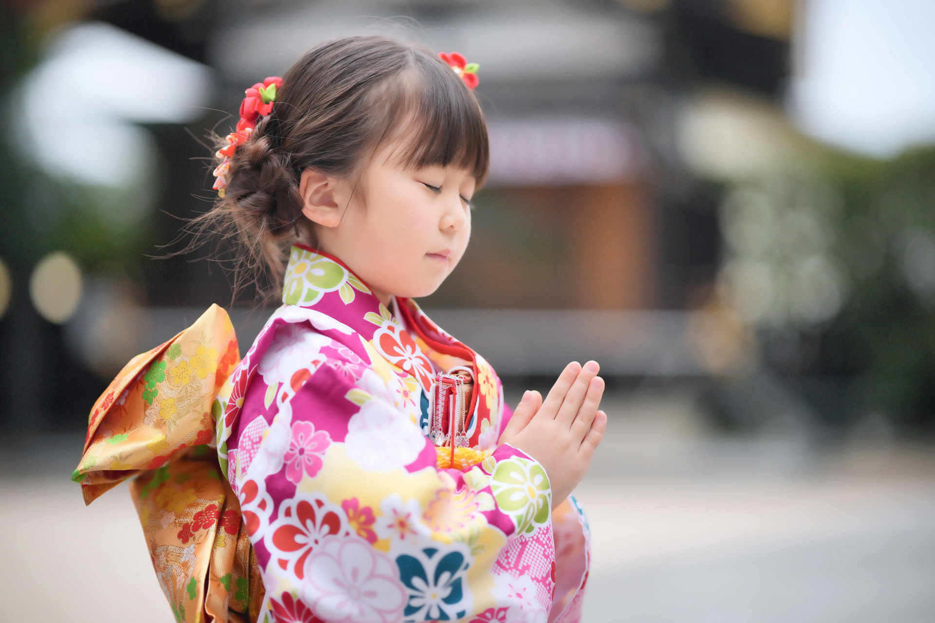 Young child in a kimono praying at a shrine.