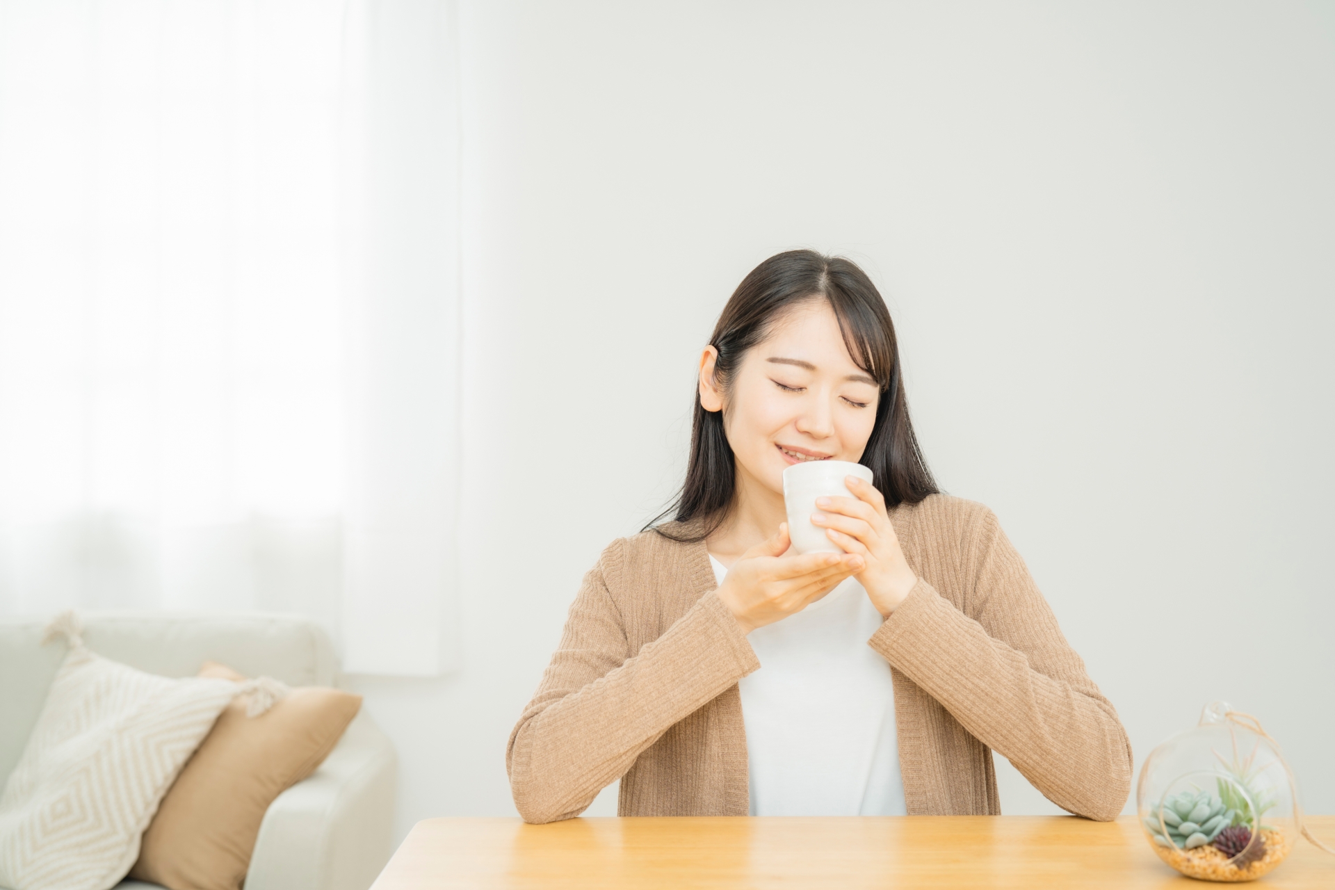 Woman holding a Japanese teacup at a table.