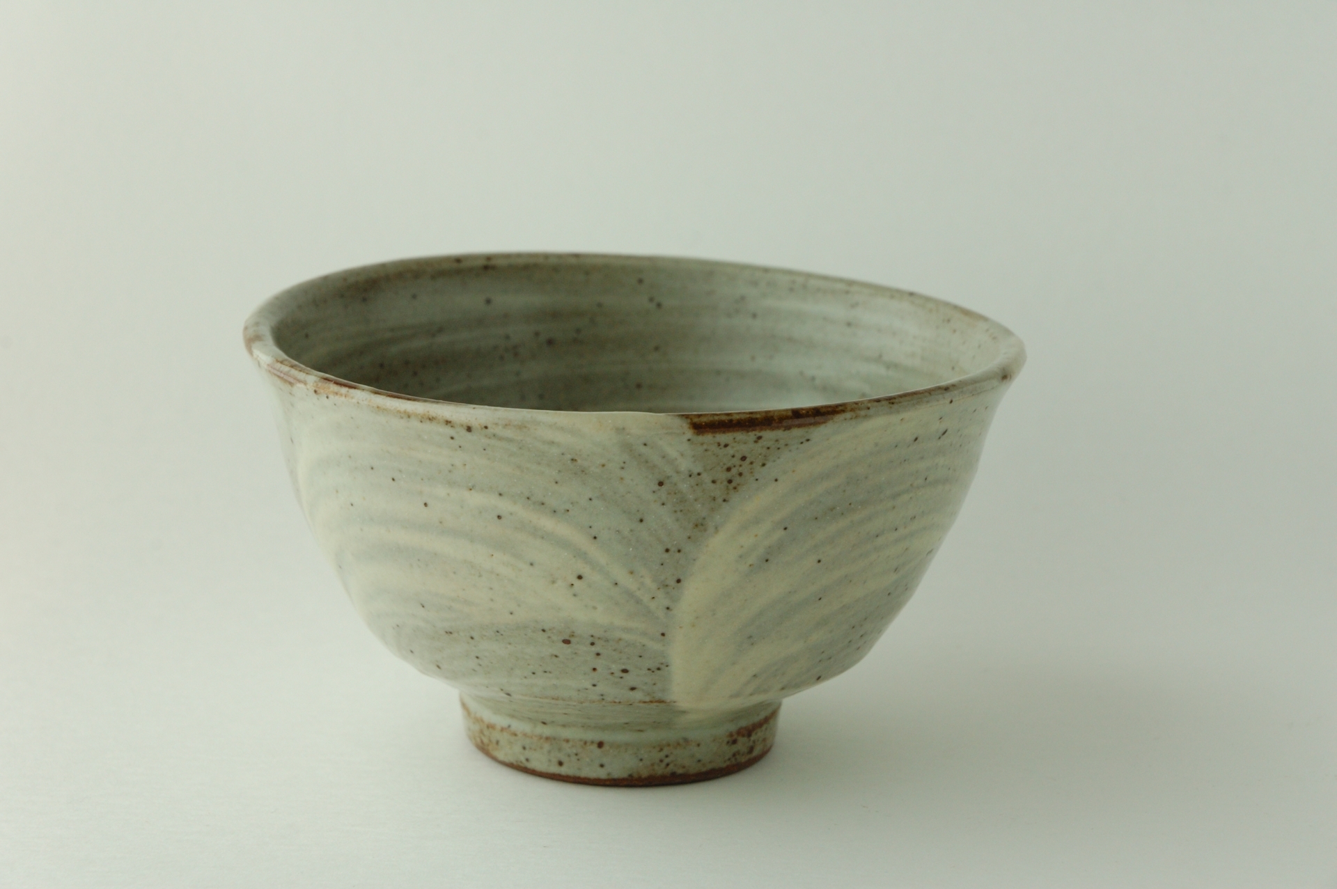 A Mashiko everyday pottery bowl with a pale glaze, speckled surface and raised foot.