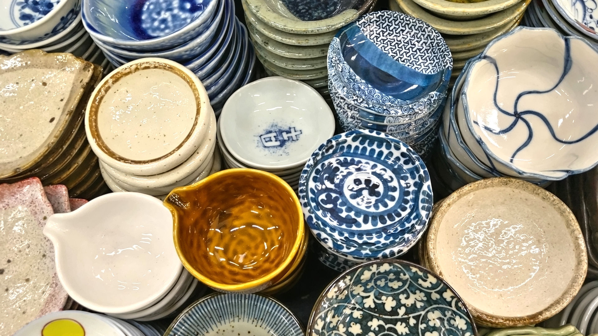 Small Japanese plates and dishes in varied shapes, glazes and patterns.