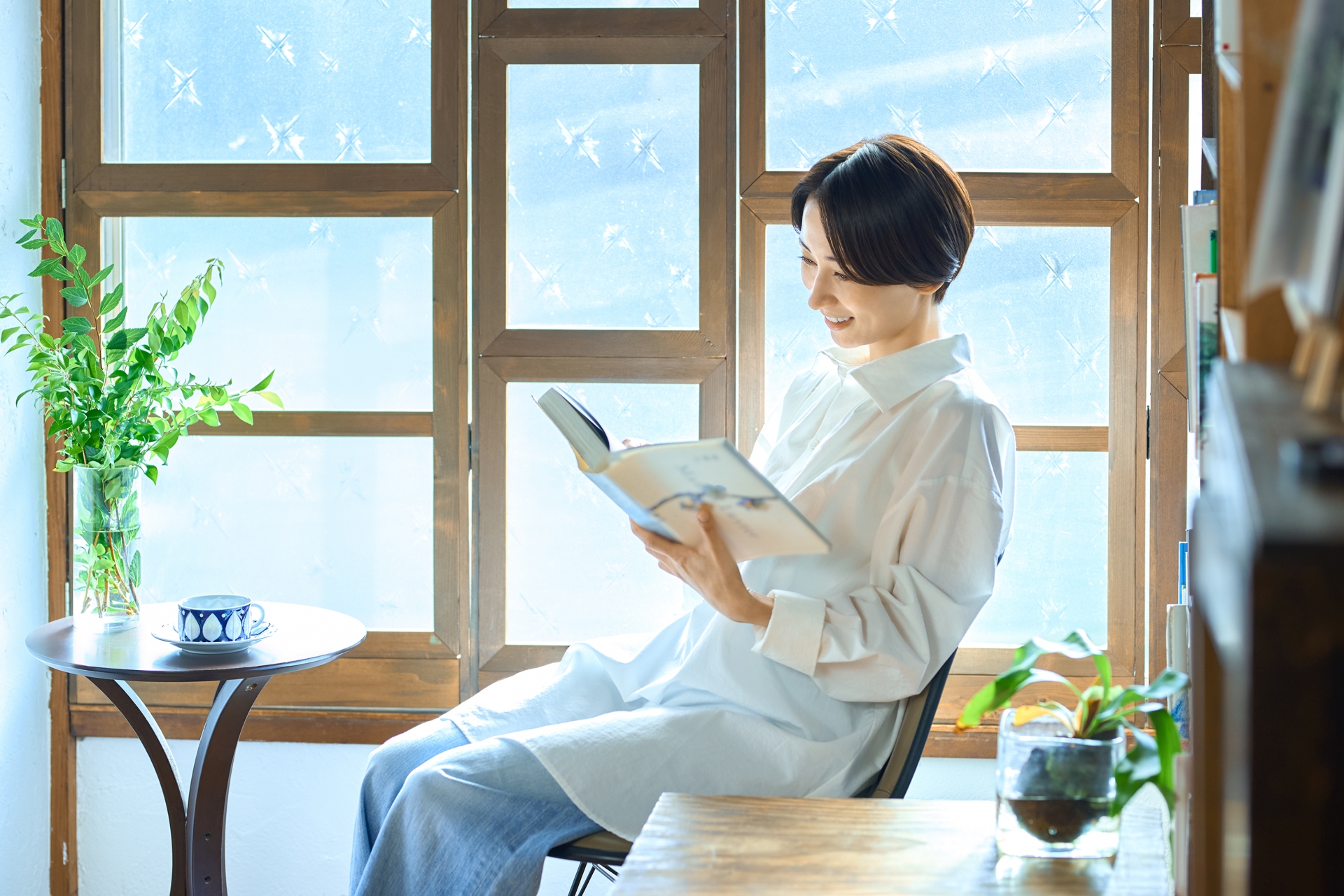 Woman reading a book beside a bright window.