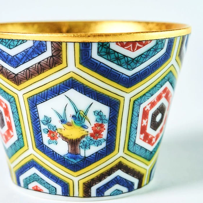 Close-up of yellow, turquoise, blue, purple and red Kutani decoration beneath a gold-leaf rim.