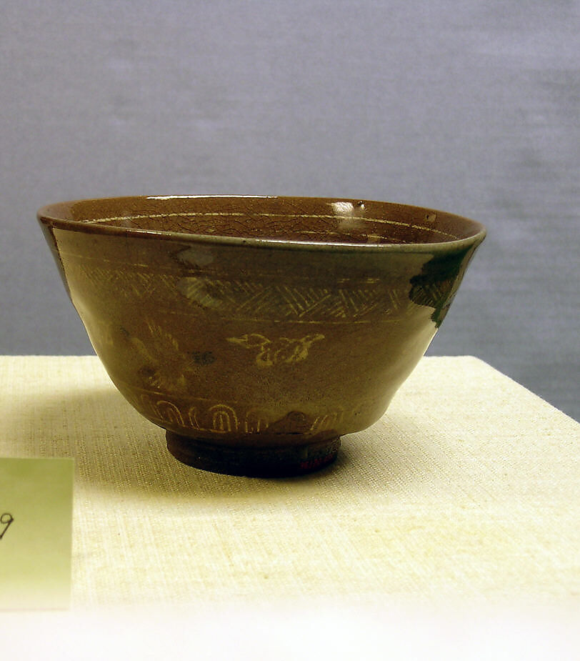 A Karatsu teabowl with a pale glaze and an inlaid white-slip design.