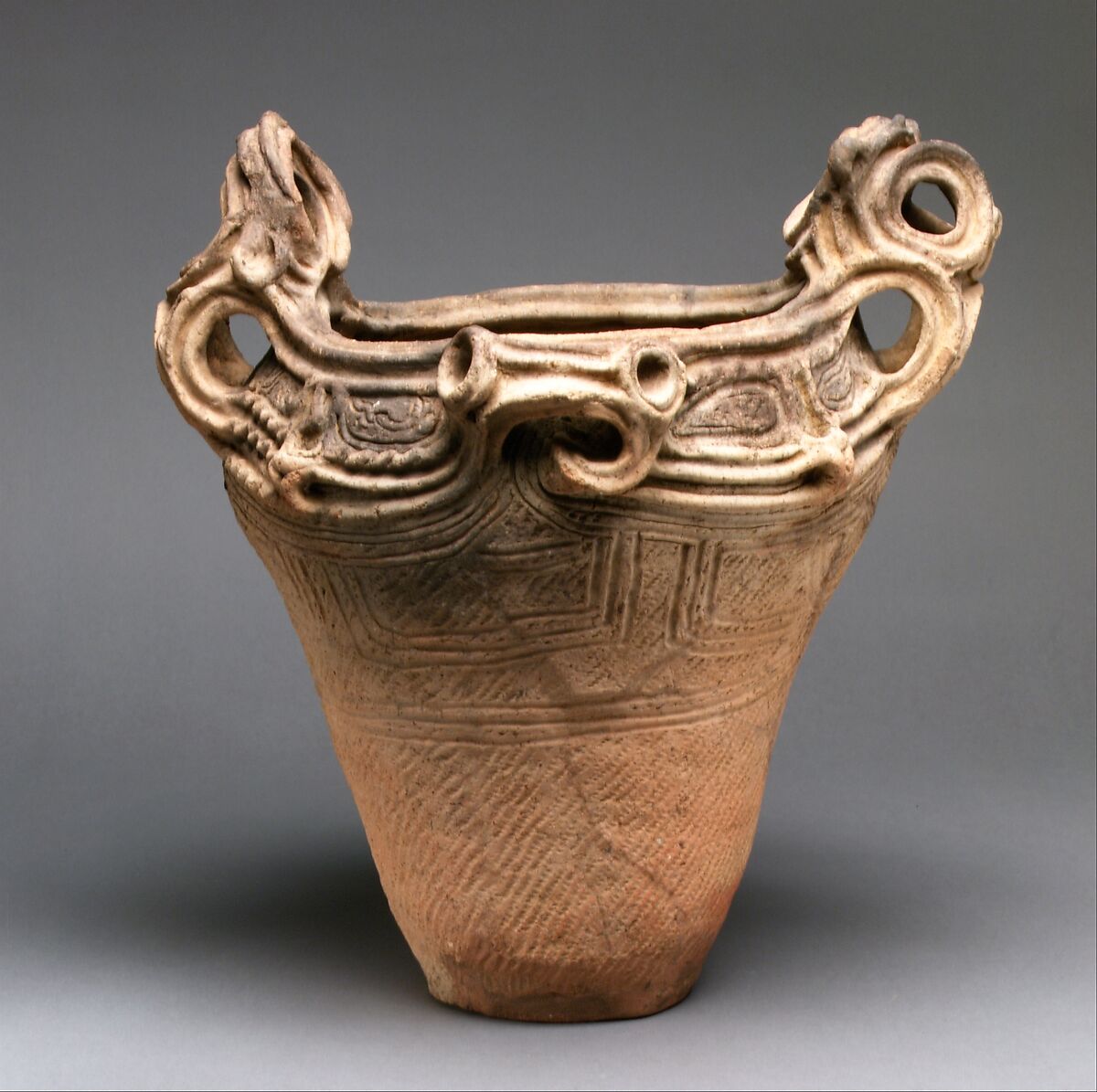 A complete Jōmon deep pot with clearly visible cord-marked clay and raised openwork handles.